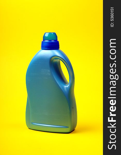 Cleaning supplies on yellow background including several spray bottles of chemicals