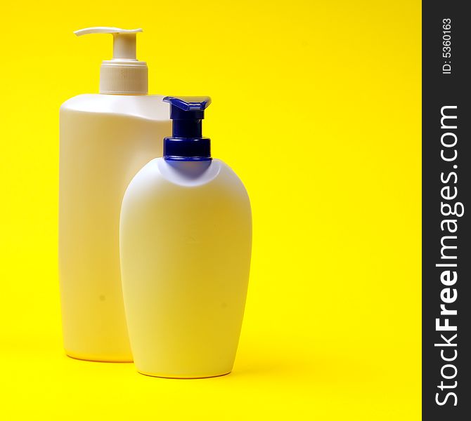 Cleaning supplies on yellow background including several spray bottles of chemicals