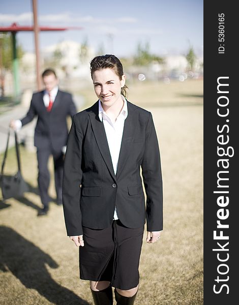 Front view of businessman and businesswoman dressed formally walking in same direction. Front view of businessman and businesswoman dressed formally walking in same direction