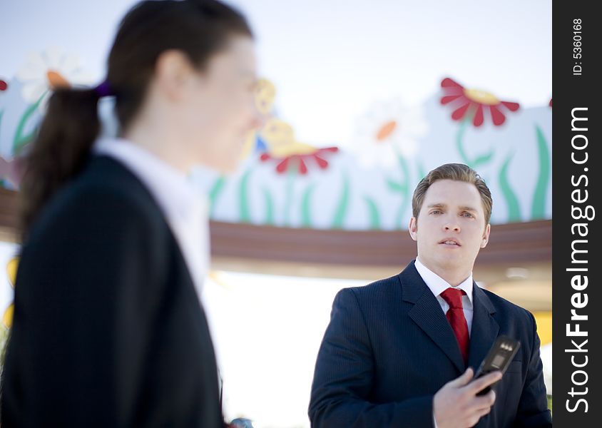 Businessman and businesswoman standing together as man uses cellphone. Businessman and businesswoman standing together as man uses cellphone