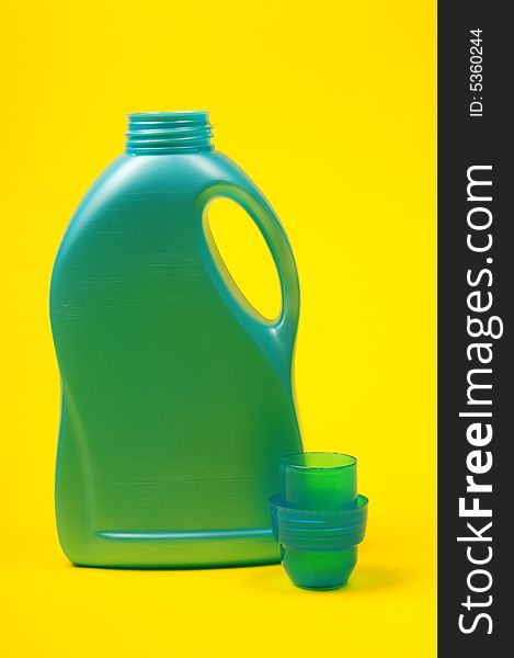 Cleaning supplies on yellow background including several spray bottles of chemicals