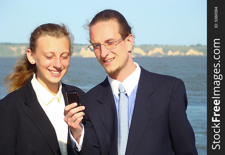 Young business man with mobile telephone and smiling girl. Rest and teaching. Young business man with mobile telephone and smiling girl. Rest and teaching.