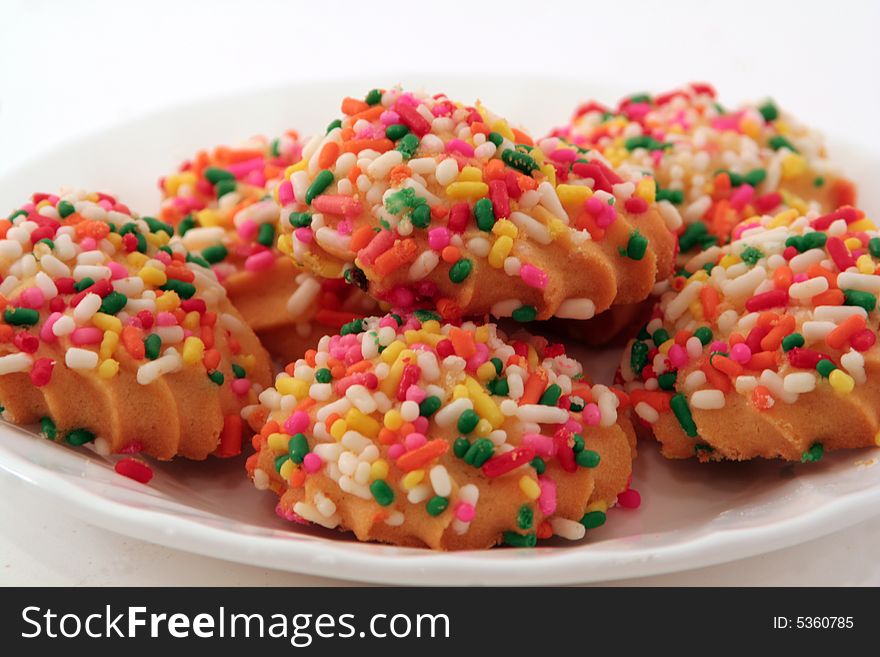 Several cookies with colorful sugar sprinkles isolated on a white plate. Several cookies with colorful sugar sprinkles isolated on a white plate