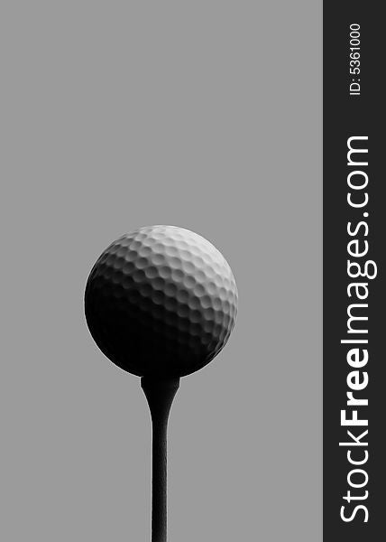 Golf ball on tee against gray with soft light.