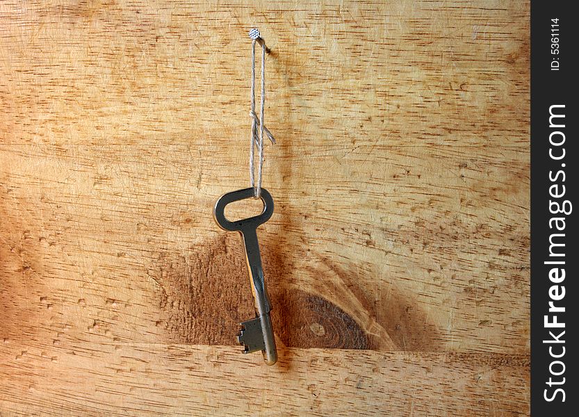 Old key hanging with cotton rope on wooden wall. Old key hanging with cotton rope on wooden wall