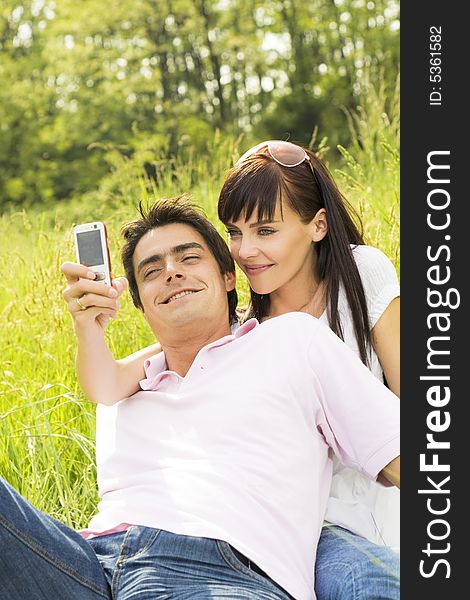 Young couple outdoors, woman taking photo with mobile phone. Young couple outdoors, woman taking photo with mobile phone