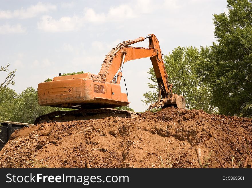 An orange front end loader on a pile of dirt. An orange front end loader on a pile of dirt