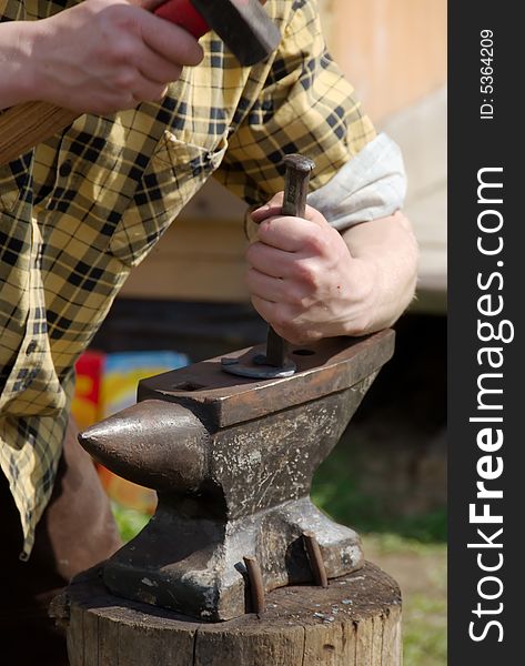 Blacksmith in the yellow shirt makes the horseshoe. Blacksmith in the yellow shirt makes the horseshoe