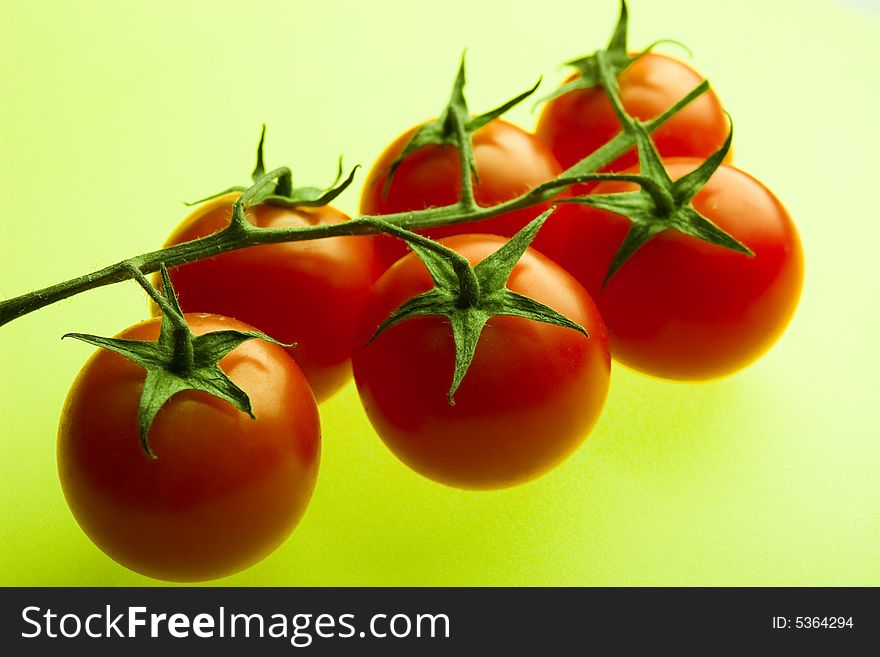 Branch of cherry tomatoes on a green background