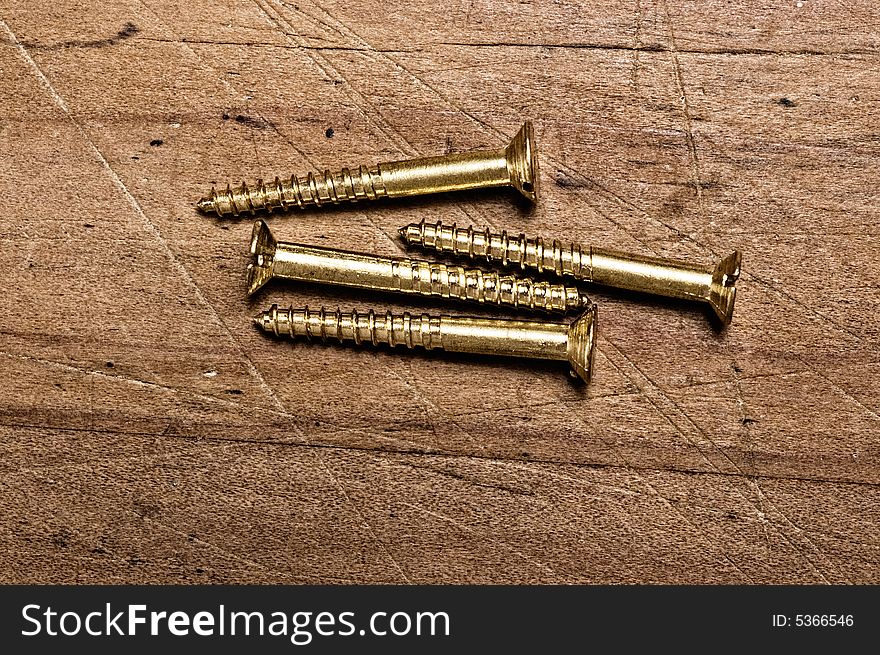 Bronze screws on wooden table, studio shot. Bronze screws on wooden table, studio shot.