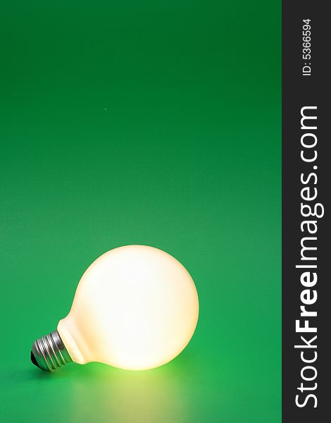 A lit up light bulb on a green background.