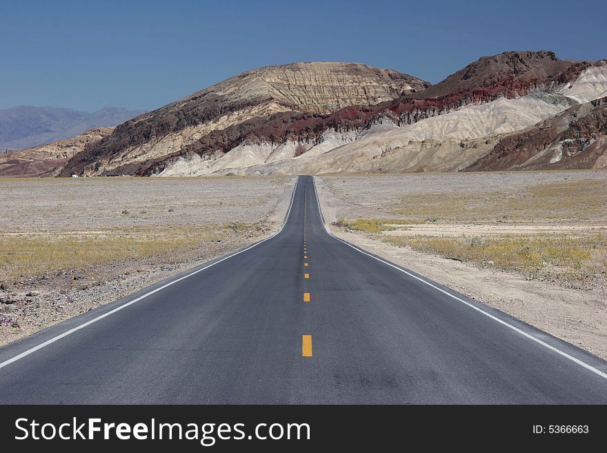 Road going to lowest part of Death Valley. Interstate road against geological feature. California. USA. Road going to lowest part of Death Valley. Interstate road against geological feature. California. USA
