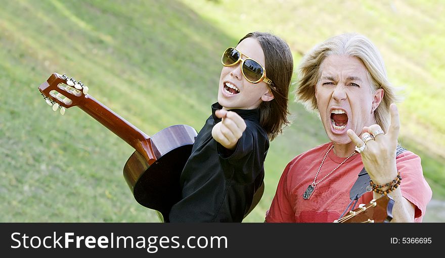 Father and son with guitars point at the camera. Father and son with guitars point at the camera