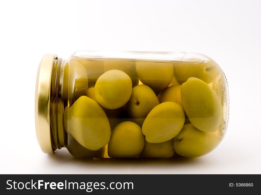 A bottle of green olives, placed over white