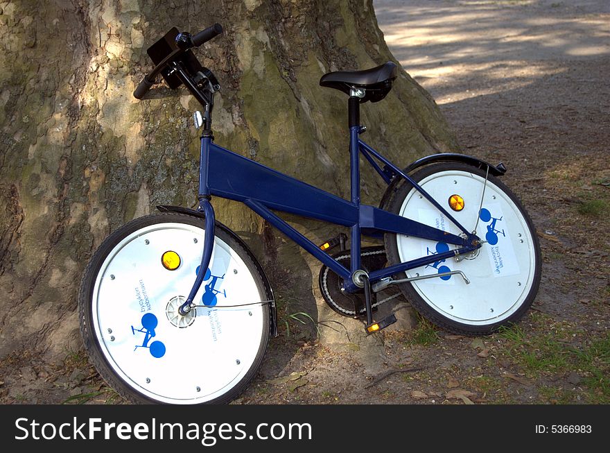 City bike parked in front of a tree.