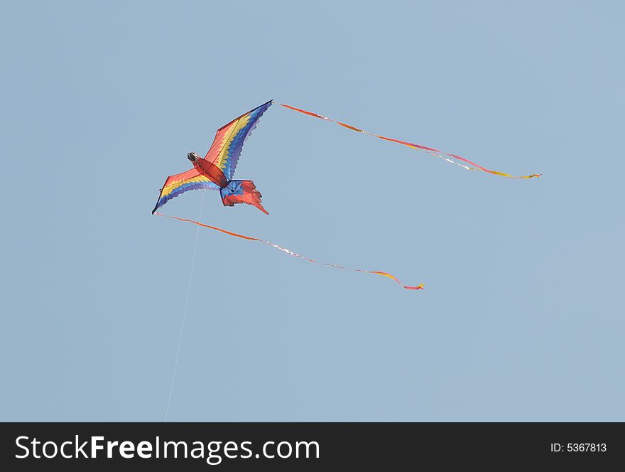 A flying parrot kite catching the sun