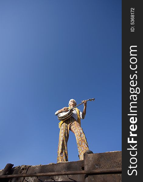 Banjo Player with groovy clothes against a wide sky