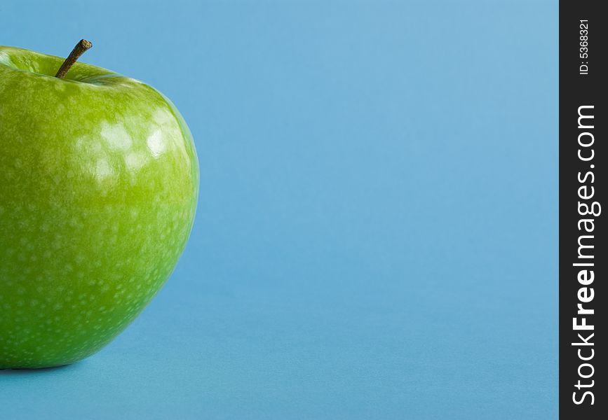 Green apple on blue background.