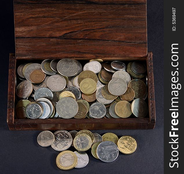 Wooden box containing a collection of many coins of different denominations from various countries. Wooden box containing a collection of many coins of different denominations from various countries