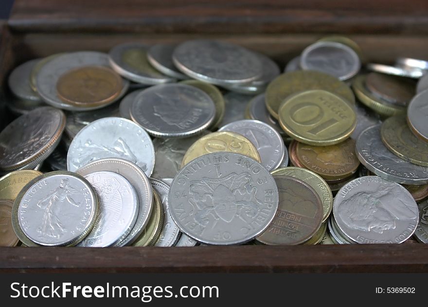Coins in international currencies collected in a box. Coins in international currencies collected in a box
