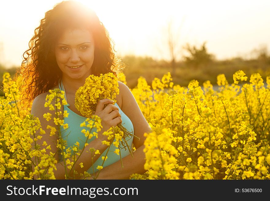 Beautiful happy woman in canola field in sunny day