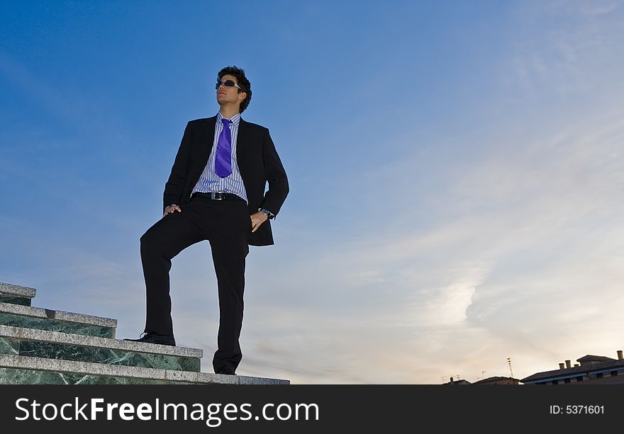 Businessman posing on stairs against blue sky. Businessman posing on stairs against blue sky.