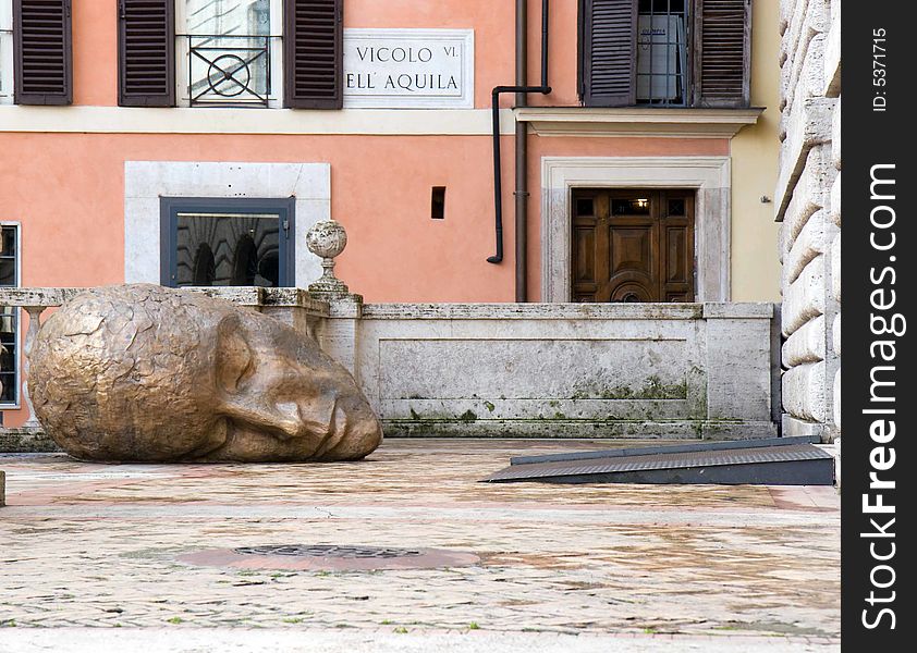 Head of a statue in a courtyard in Rome, Italy (italian street sign on the wall)