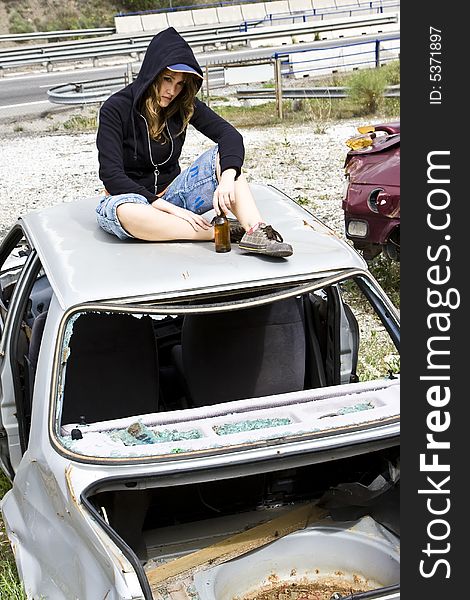 Young woman taking beer in the scrapyard. Young woman taking beer in the scrapyard