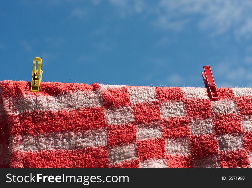 Clothes pegs holding woolen cloth on a string against the blue sky. Clothes pegs holding woolen cloth on a string against the blue sky