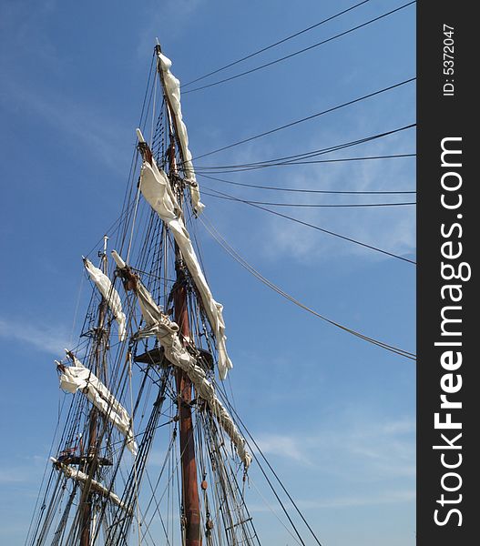 Bottom view of mast, sails and rigging of an old sailing boat  against a blue sky with some light clouds. Bottom view of mast, sails and rigging of an old sailing boat  against a blue sky with some light clouds