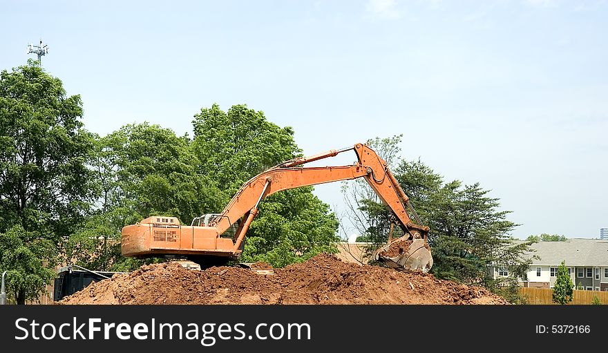 An orange front end loader on a pile of dirt. An orange front end loader on a pile of dirt