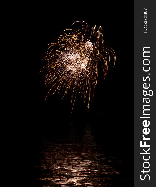 Yellow explosion of fireworks in the black night sky and its reflection in water. Yellow explosion of fireworks in the black night sky and its reflection in water