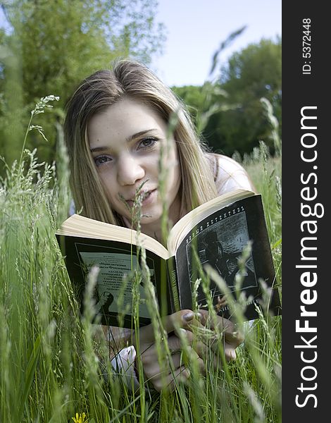 Girl on grass reading a book