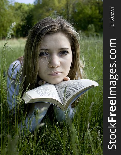 Girl reading a book on meadow