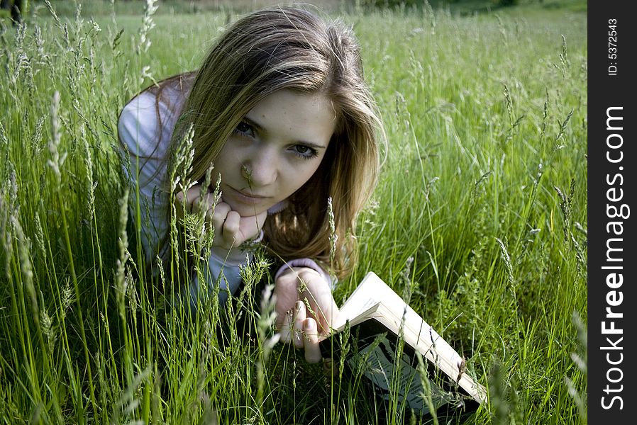 Girl reading a book on meadow