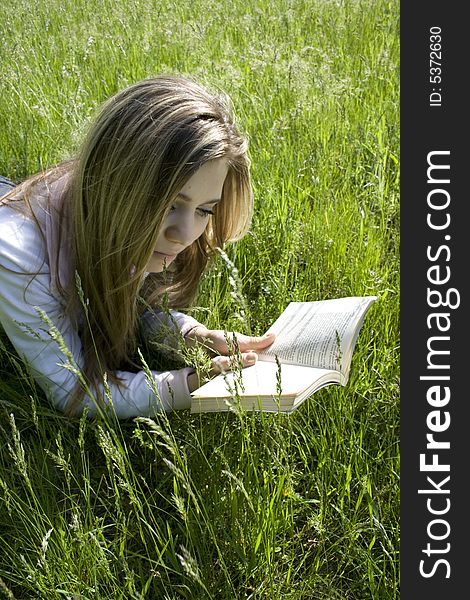 Girl reading book on grass