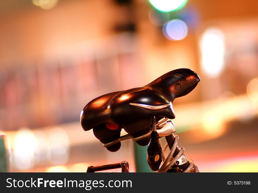 Bike seat set against blurred lights at night. Space for copy