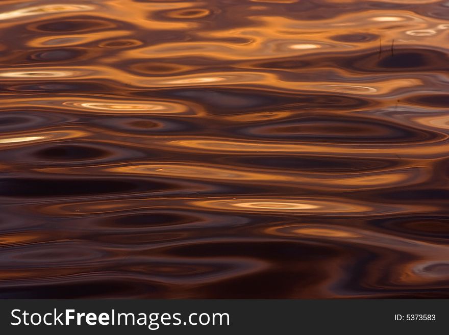 Colorful reflections on a water surface. Reflection of the sky at a sunset.