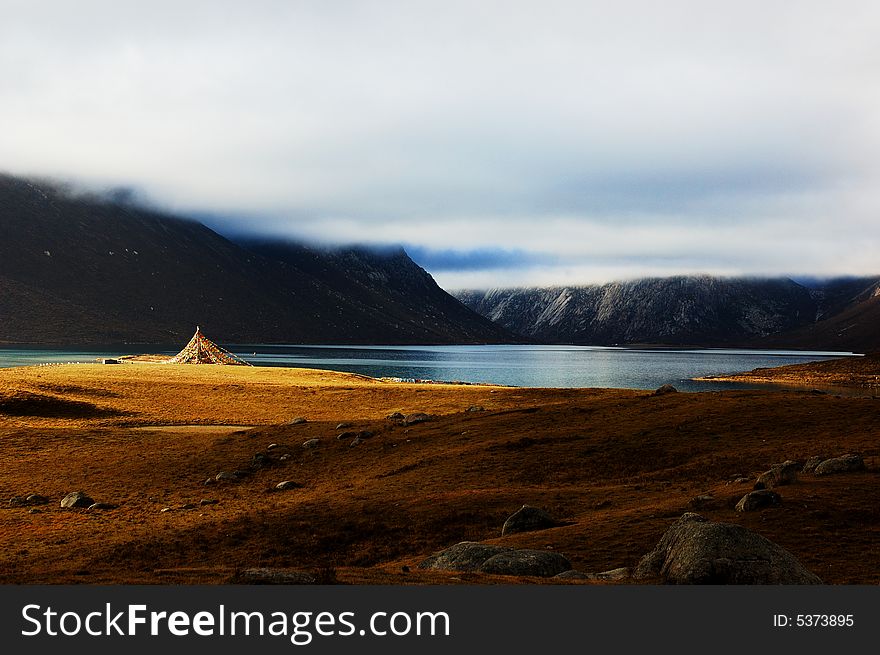 When travelling in Tibet of China, a beautiful lake appears in front of us, and the meadows in autumn is so beautiful too, with a flag on it. When travelling in Tibet of China, a beautiful lake appears in front of us, and the meadows in autumn is so beautiful too, with a flag on it.