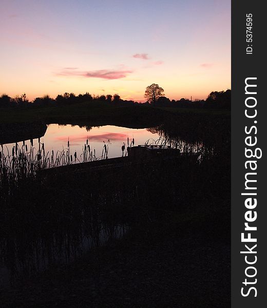 Small boat nestled in reeds by waters edge at dusk. Small boat nestled in reeds by waters edge at dusk.