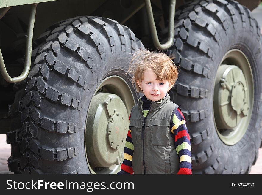 Portrait of the boy on a background of the big wheels of military technics