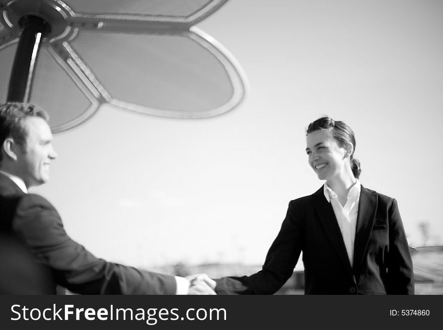 Businessman and businesswoman standing and shaking hands in front of large yellow flower. Businessman and businesswoman standing and shaking hands in front of large yellow flower