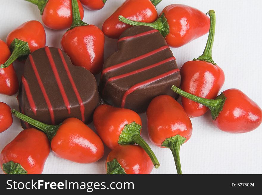 Red Chillies and Heart shaped chocolates on a white background. Red Chillies and Heart shaped chocolates on a white background