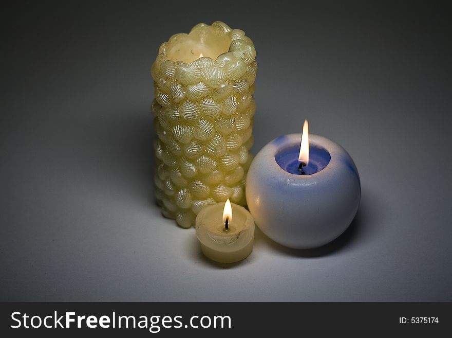 Three burning candles on a grey background. Three burning candles on a grey background