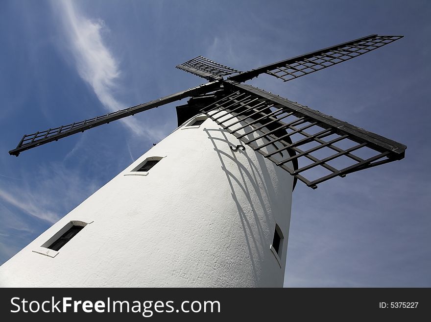 White windmill with black sails against blue sky