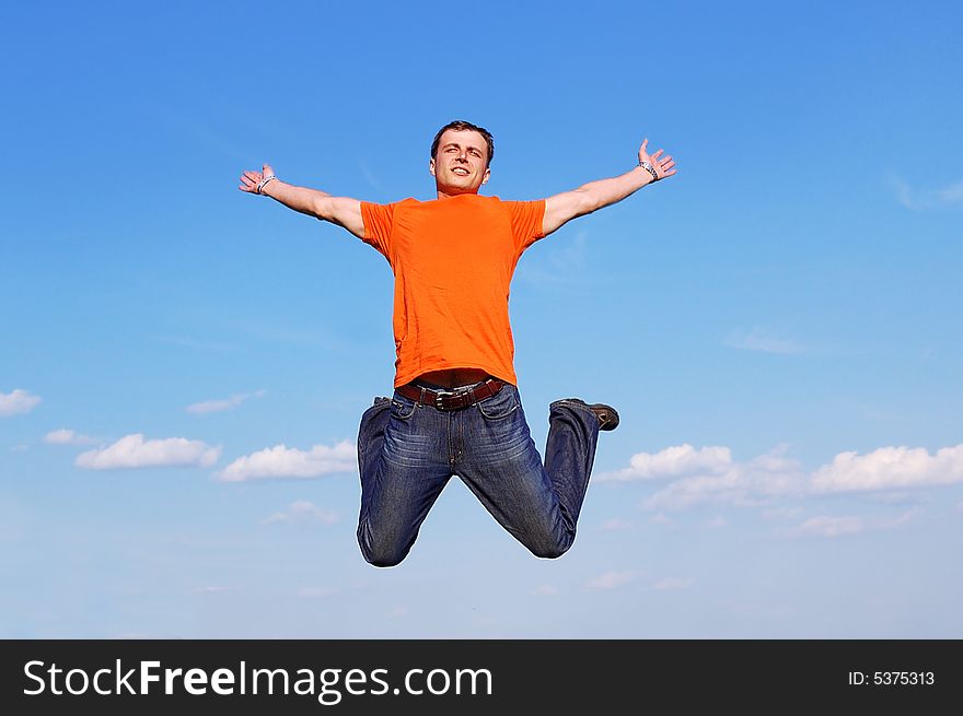 Happy young man in red t-shirt jumping high at the blue clear sky background. Happy young man in red t-shirt jumping high at the blue clear sky background