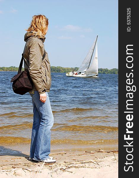 Girl-photographer looking to the white yacht at the river. Girl-photographer looking to the white yacht at the river