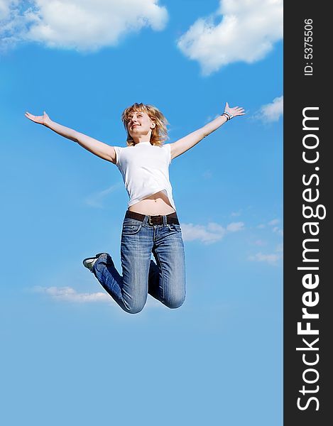 Happy young  woman in white t-shirt jumping high at the blue clear sky background. Happy young  woman in white t-shirt jumping high at the blue clear sky background
