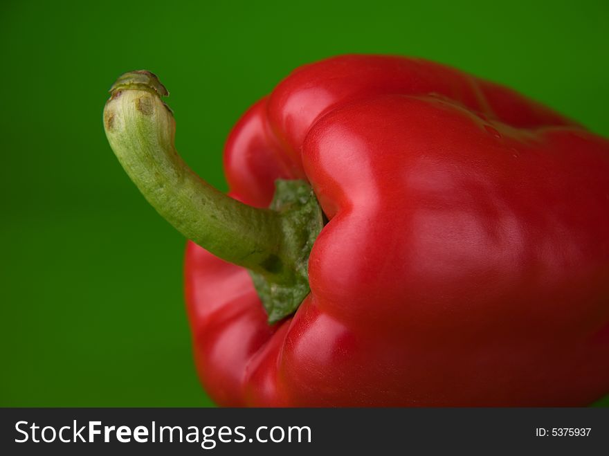Close photo of a red paprika on the green background