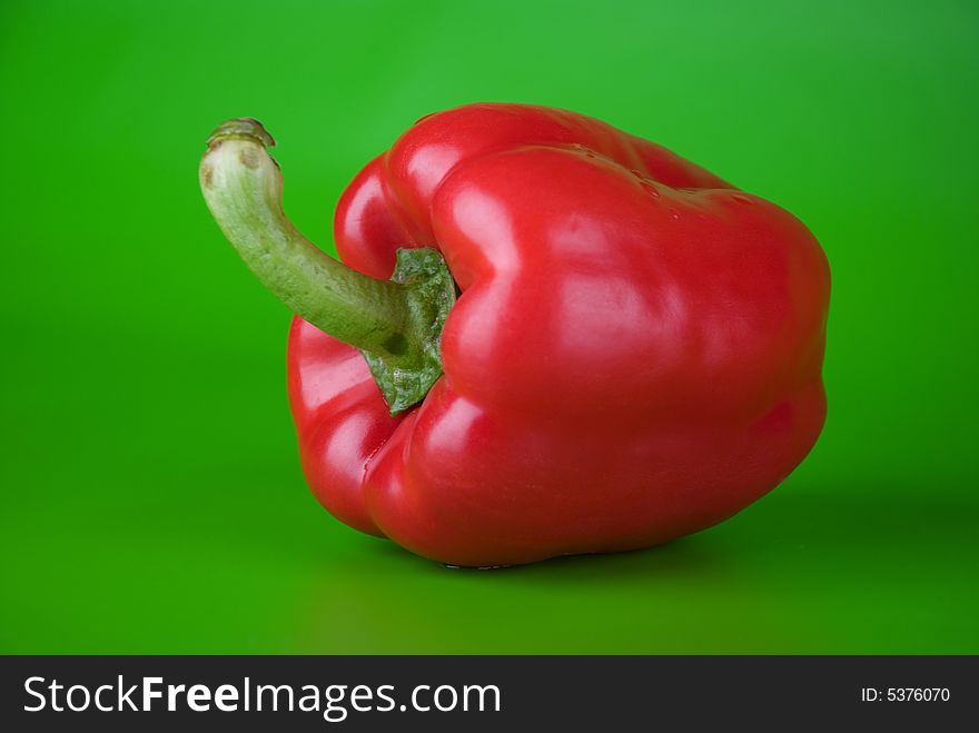 Red paprika on the green bright background